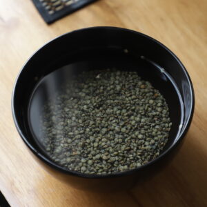 Green lentils soaking in a black bowl.