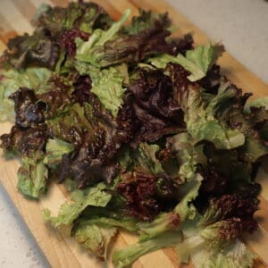 Pile of torn red leaf lettuce on cutting board.