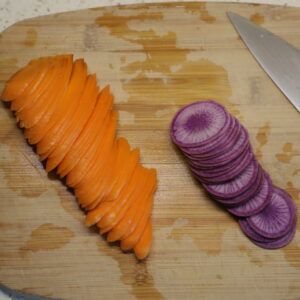 Carrot and radish slices on a cutting board, neatly stacked and ready to be cut further.