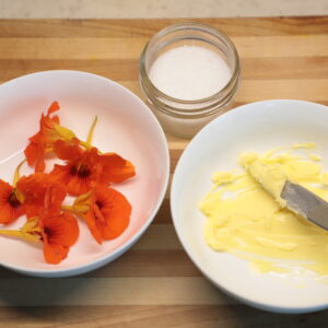 White bowl with orange nasturtium flowers, another with butter, and a third dish with salt.