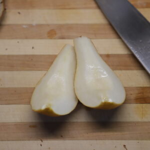 Two pear quarters and blade on cutting board.