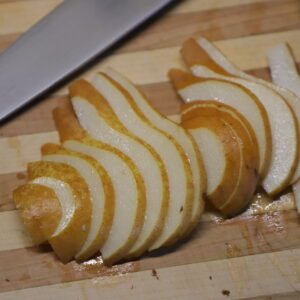 Bosc pear slices and blade on board.