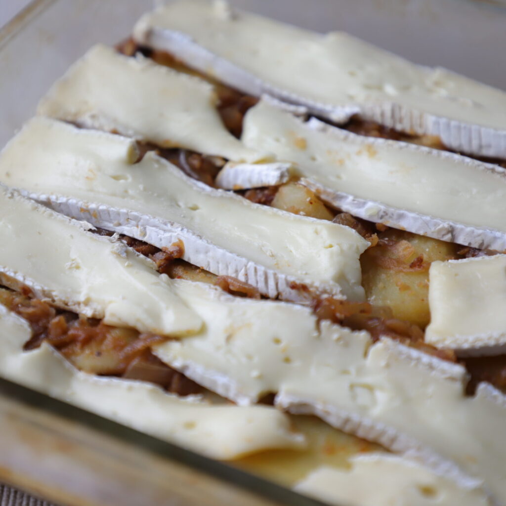 close up of tartiflette with its slices of brie before baking
