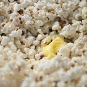 Close up of cream-colored popcorn with a piece of butter melting in it.