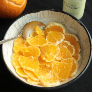Bright orange salad in a bowl with a spoon and showing juicy slices of fruit.