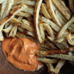 Close up of celeriac fries and bright orange mayo-based samurai sauce.
