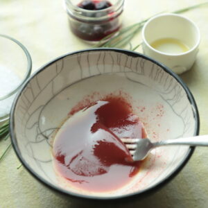 Purple-colored vinaigrette made with blueberry vinegar being whisked in a bowl.